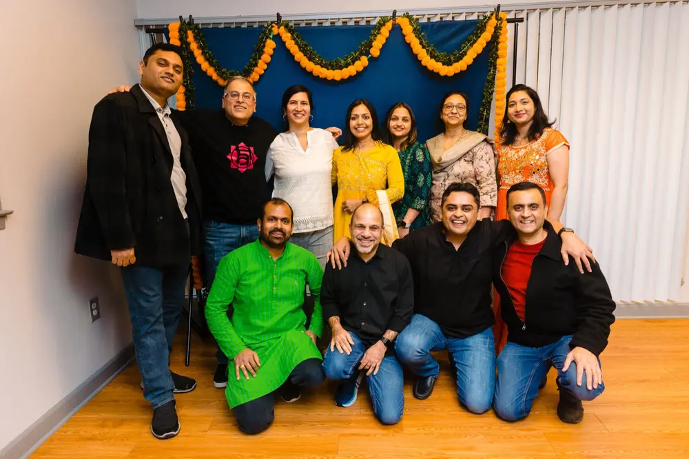 aadhyatmik volunteers pose together in front of a marigold garland backdrop