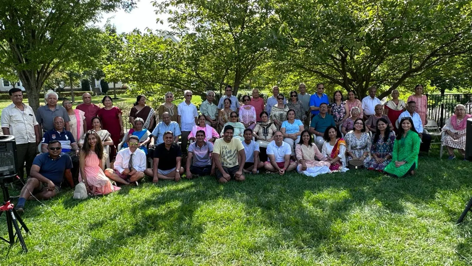 A large aadhyatmik community group photo on a lawn under the trees