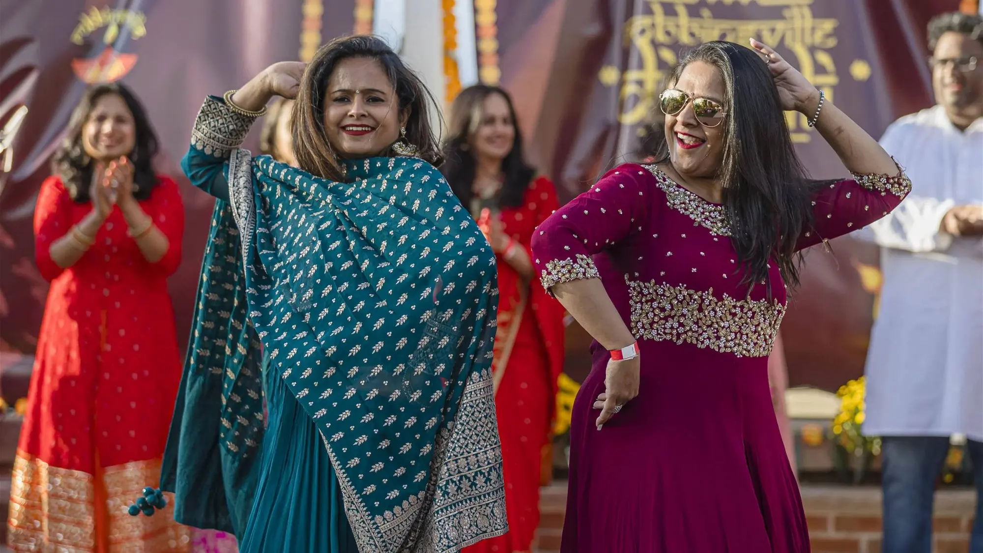 Women in teal and magenta outfits dance at the Robbinsville Diwali celebration