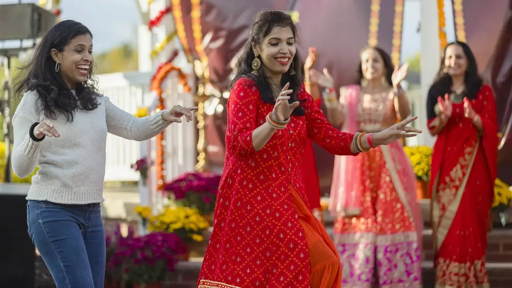 Women in red and pink outfits dance together at the Robbinsville Diwali celebration