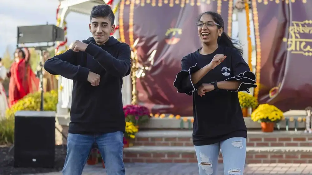Two young dancers perform a hip-hop routine in front of the Diwali stage backdrop