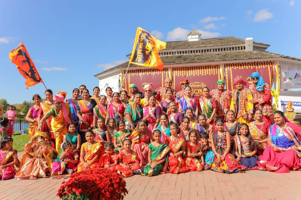A troupe of dancers and parade walkers posing under blue sky at the Town Center lake gazebo