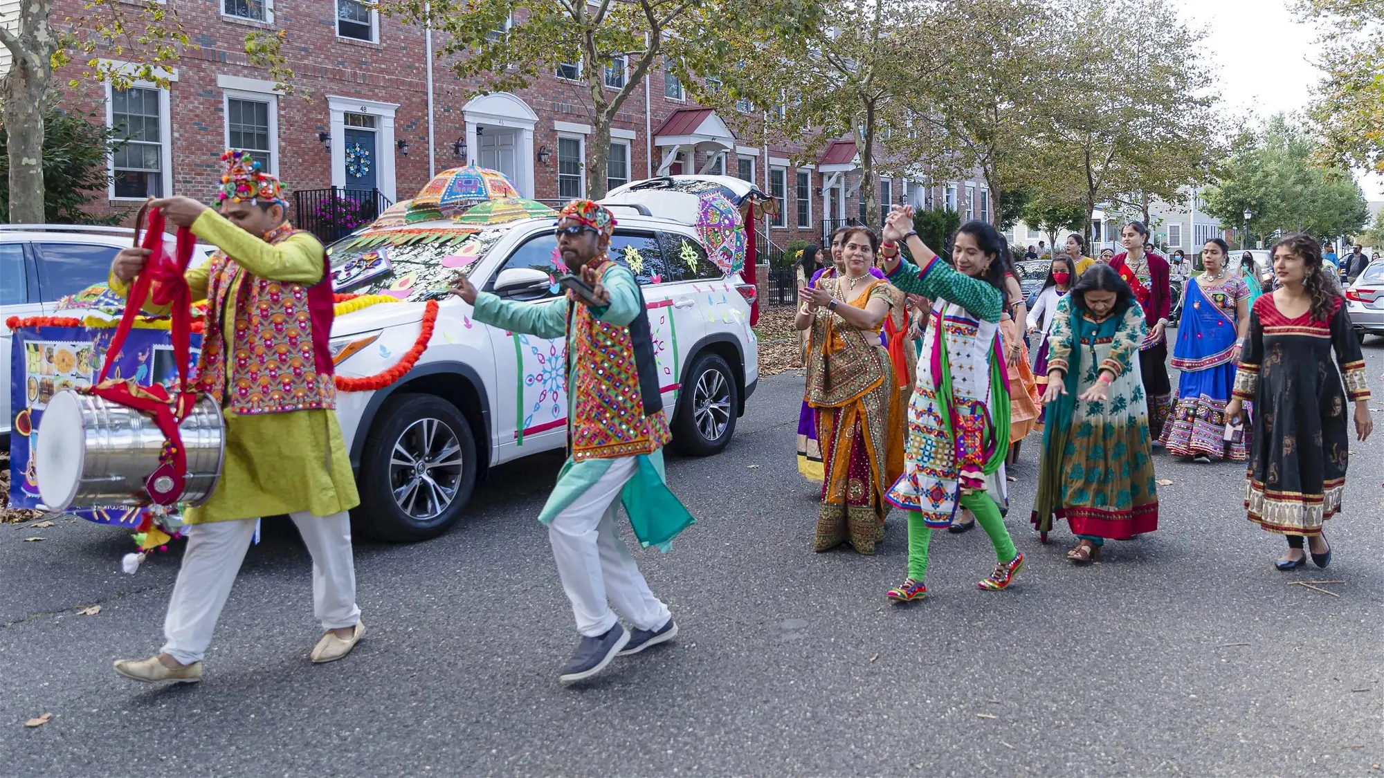 Folk dancers perform beside a decorated float on the Diwali Parade route