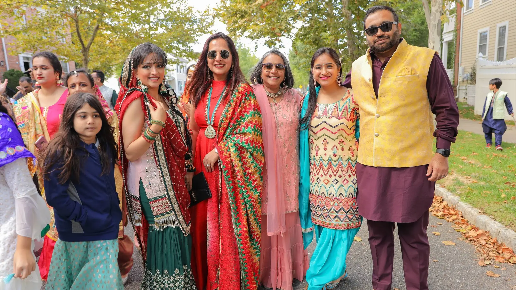 Three generations of one aadhyatmik family smiling together in festive dress on the Diwali Parade route