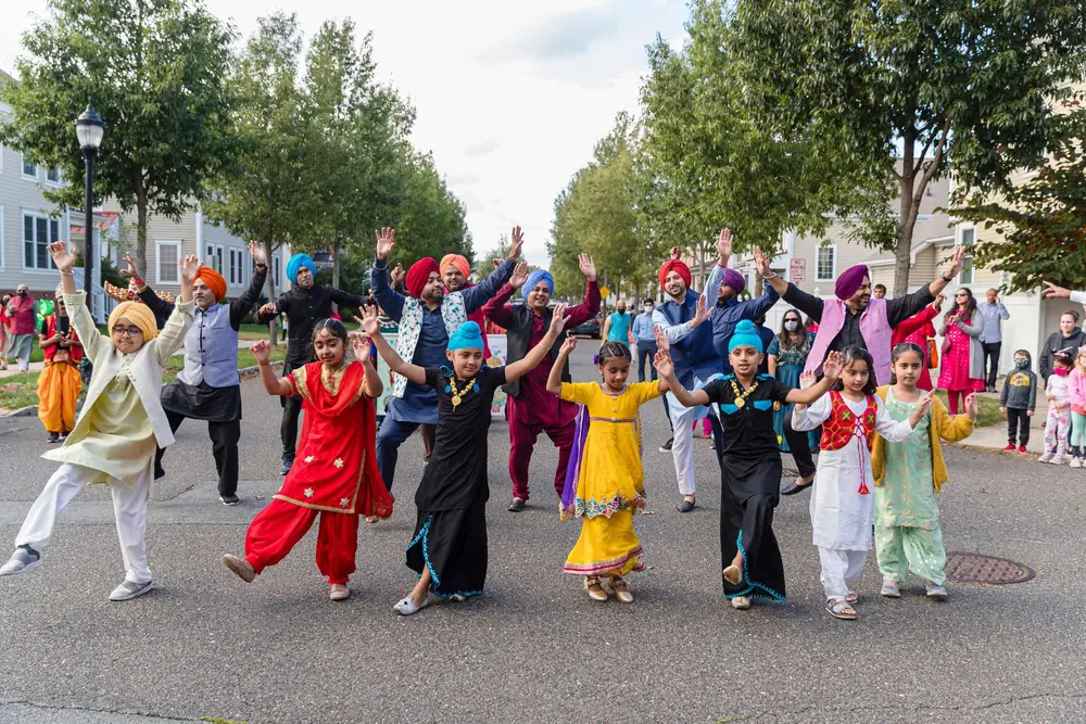 Parade walkers of every age dance down a Robbinsville street with arms raised during the Diwali Parade