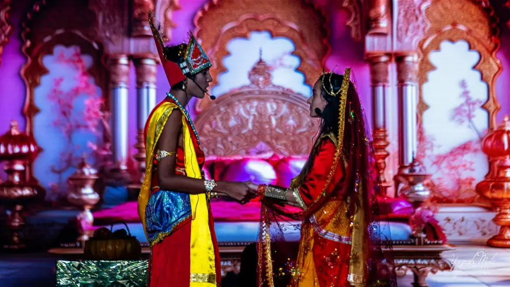 Actors in Ramleela costume perform a scene under purple stage light at Diwali