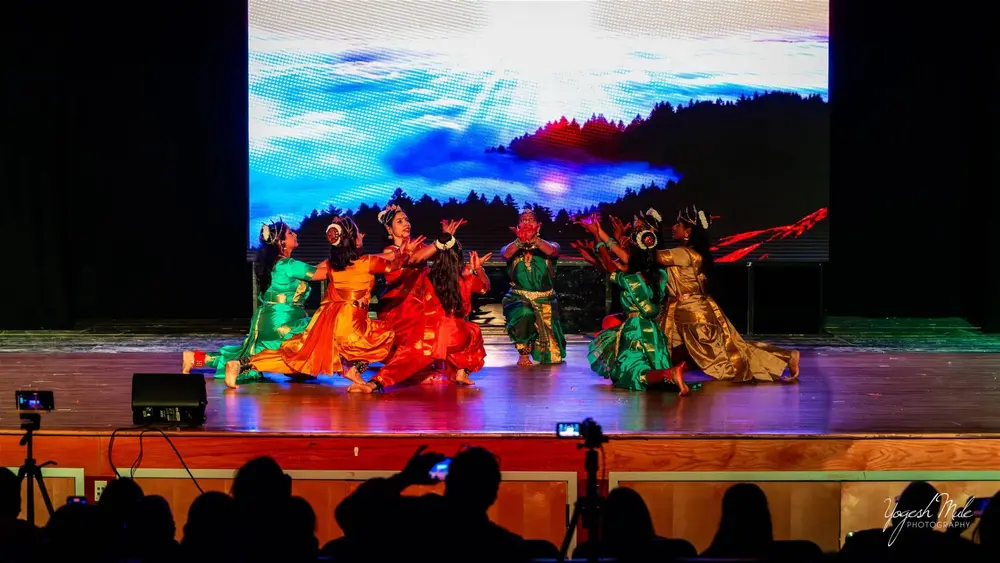 Dancers perform under blue and orange stage light at the Diwali cultural show
