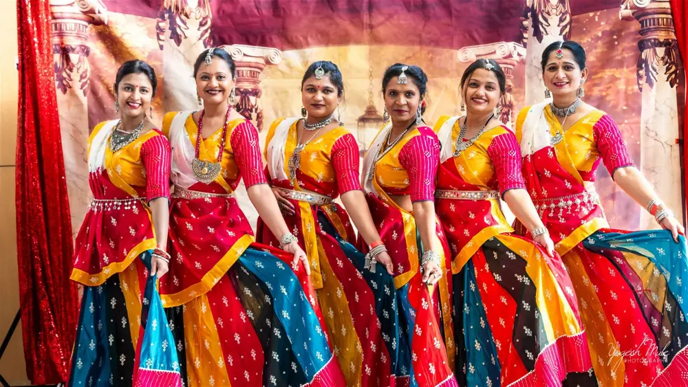A line of dancers in red and yellow lehengas performs a classical piece on the Diwali stage
