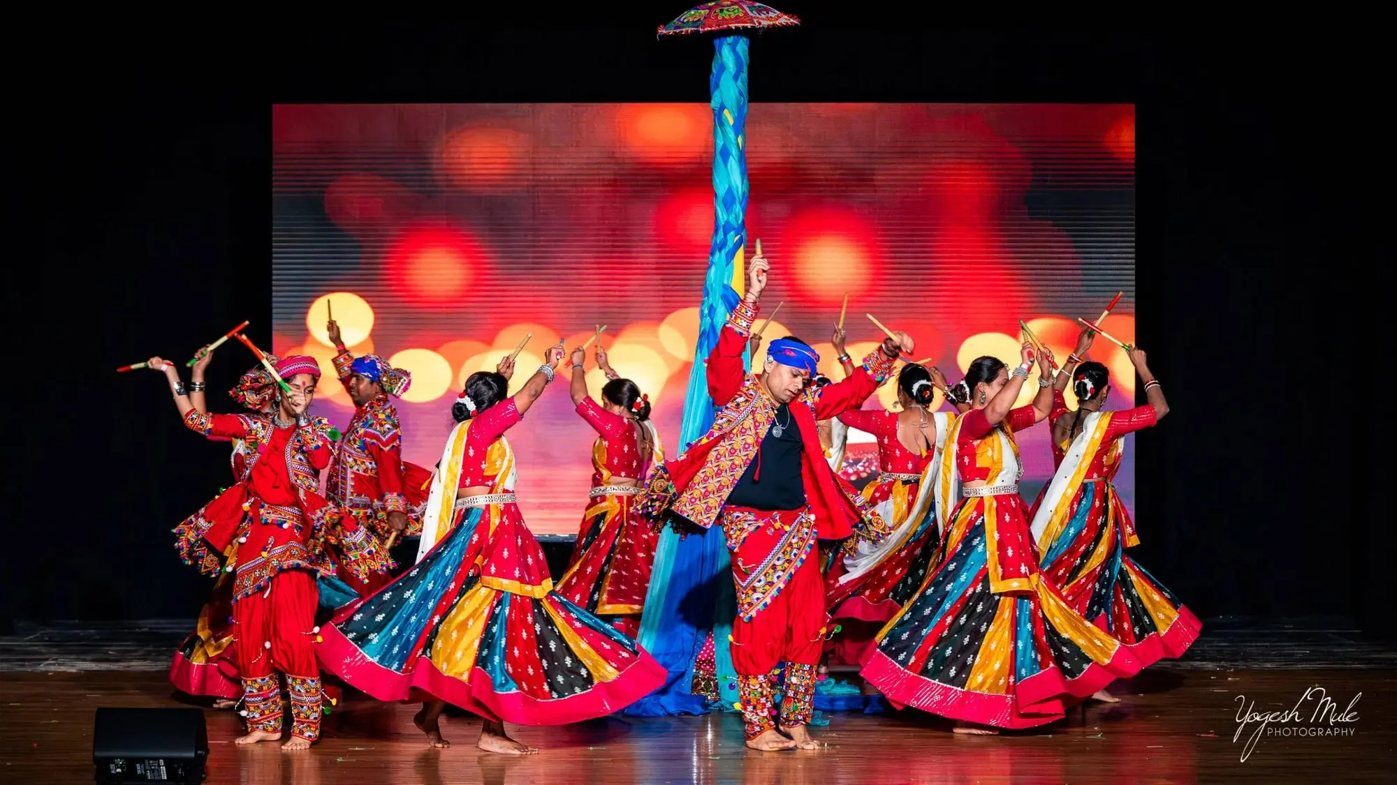 Dancers in mirrored chaniya choli spin through a garba performance on stage