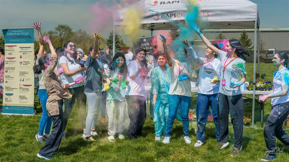 A burst of coloured powder fills the air as the crowd celebrates Holi