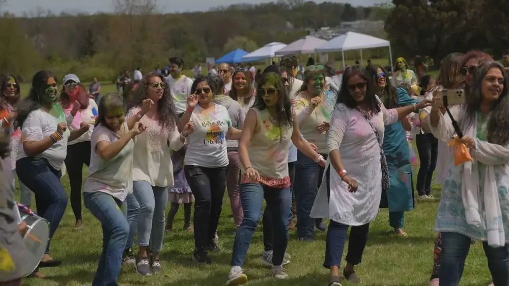 A crowd dances on an open field during the Robbinsville Holi celebration