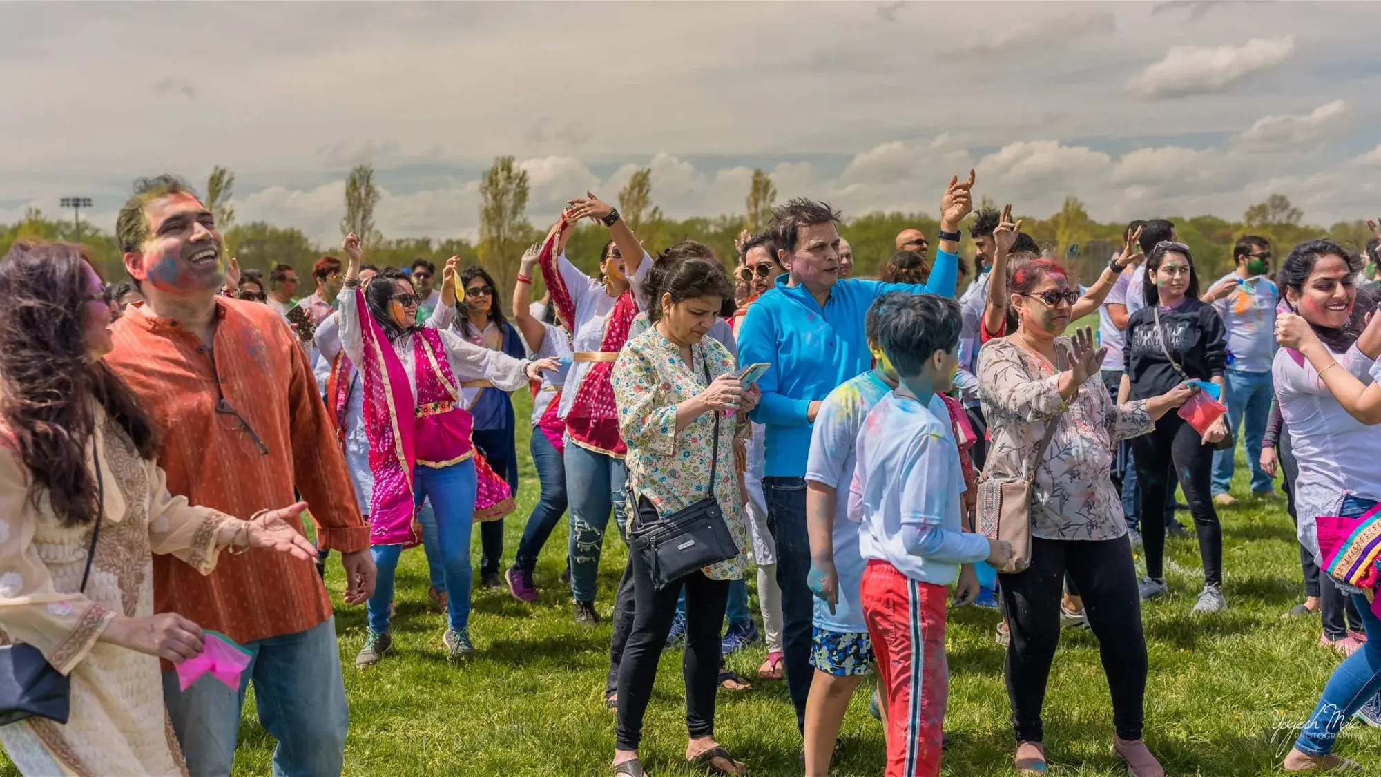 Families dance together in Holi colour on the open lawn