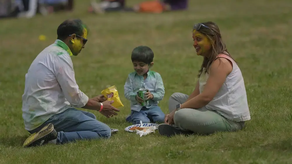 A family sits on the grass together during the Holi festivities