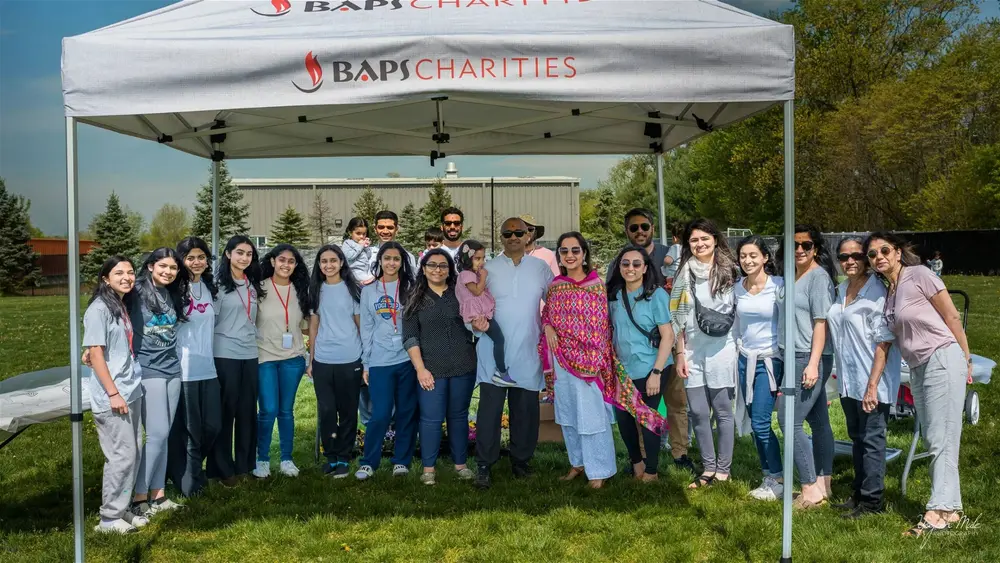 Volunteers and families gather under a charity tent at Robbinsville Holi