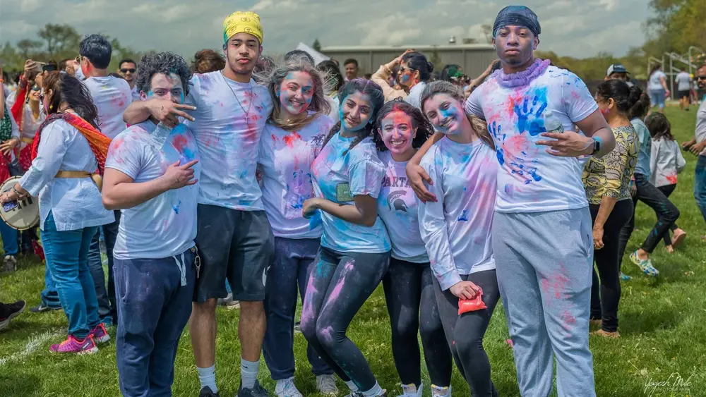 Teenagers covered in Holi colour cheer together