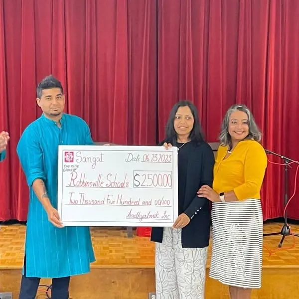 A youth volunteer presents a donation with community members