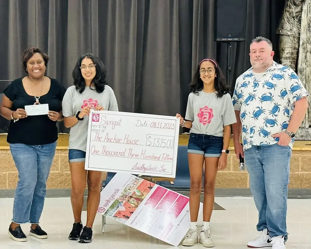 A youth leader and volunteers present a charity cheque raised through aadhyatmik events