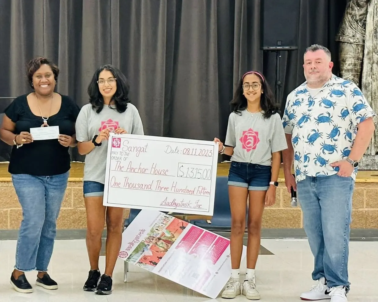 A youth leader and volunteers present a charity cheque raised through aadhyatmik events