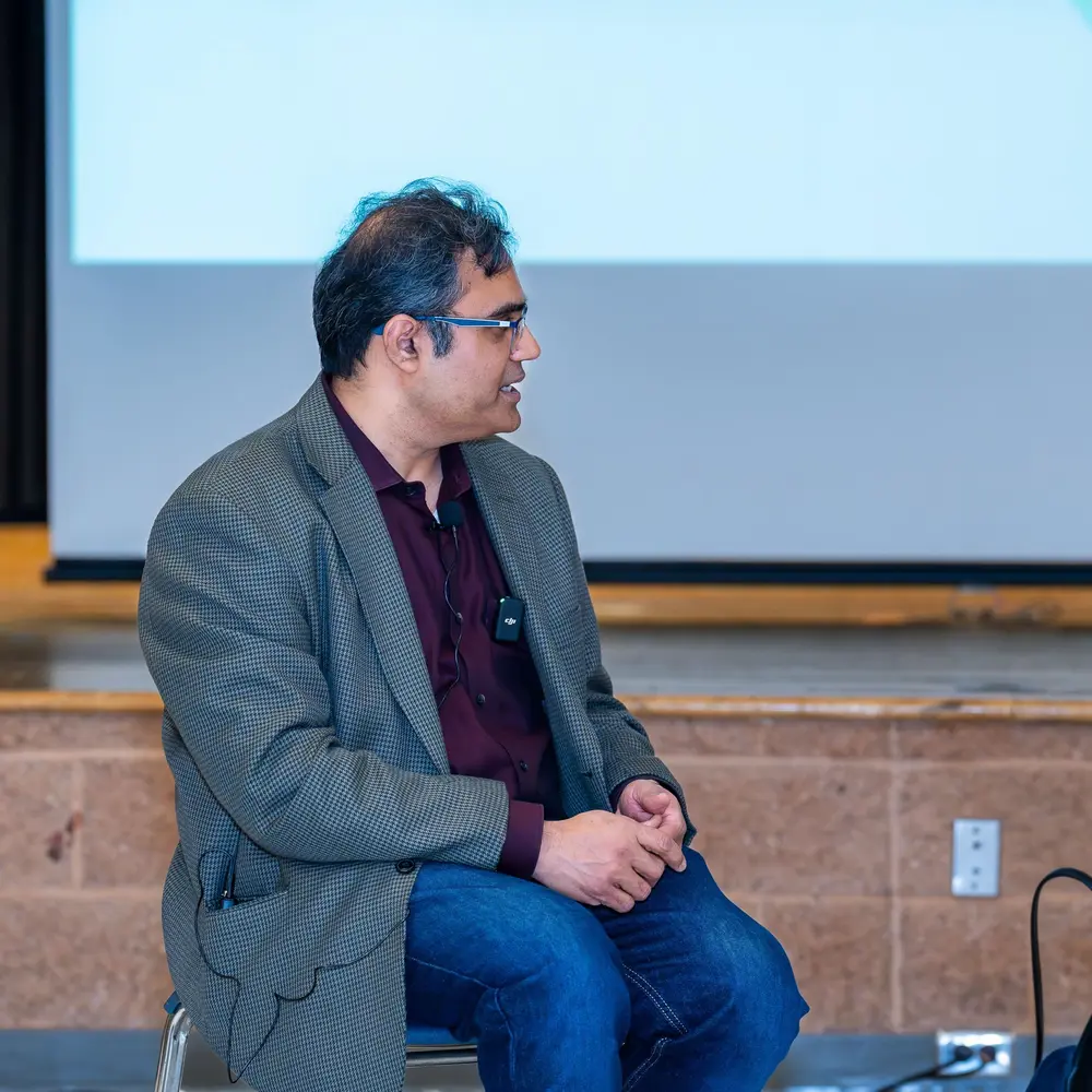 A speaker in conversation on stage at a Sangat event