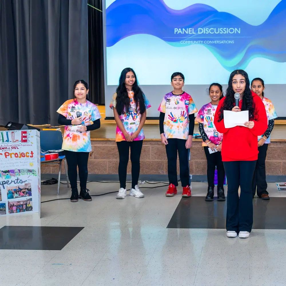 Youth panelists stand in front of the panel discussion slide at Sangat