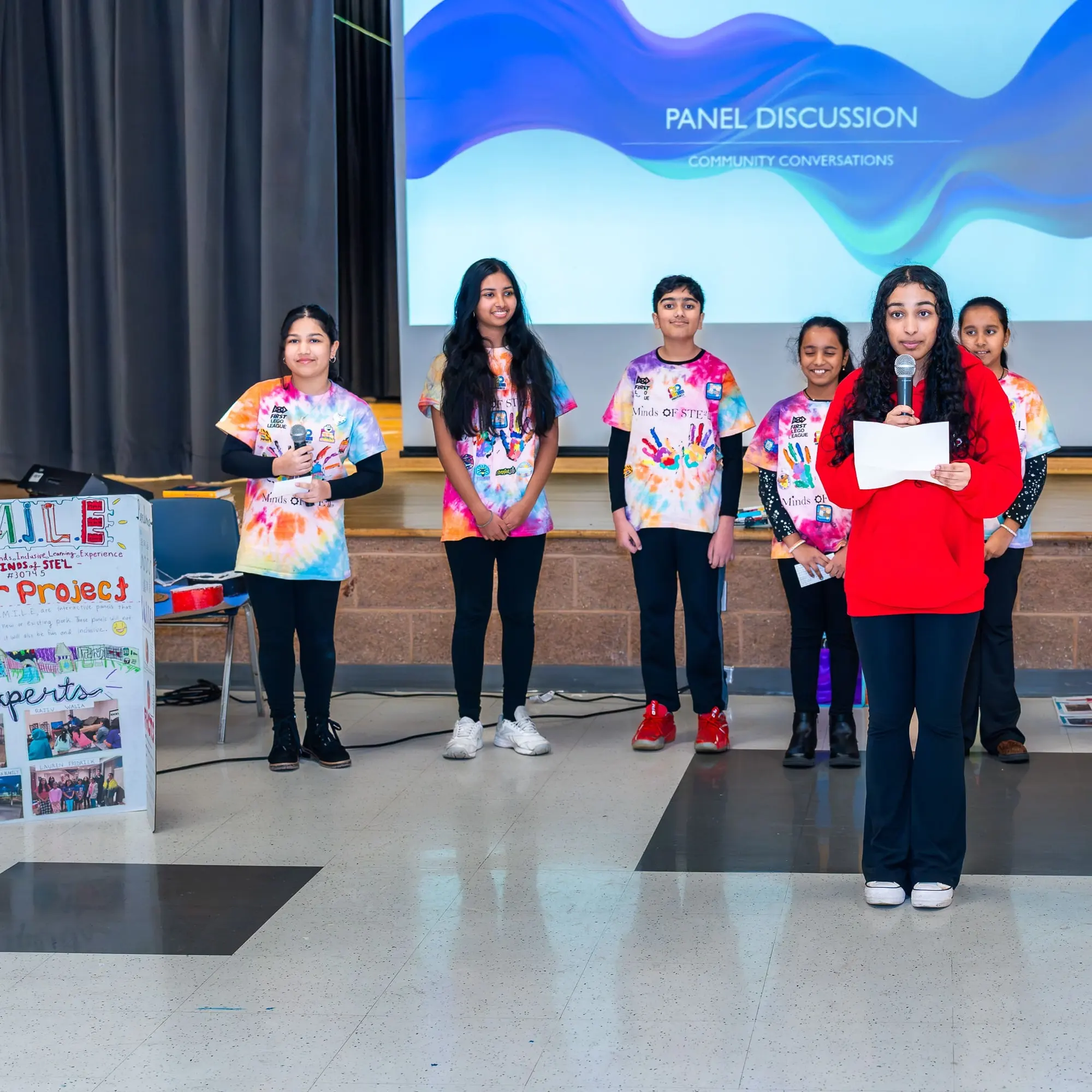 Youth panelists stand in front of the panel discussion slide at Sangat
