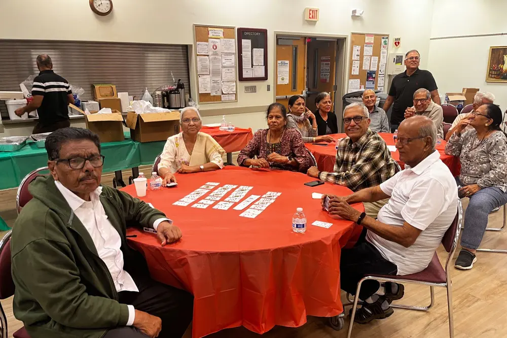 Seniors talk across a red table at a Sanskriti games evening