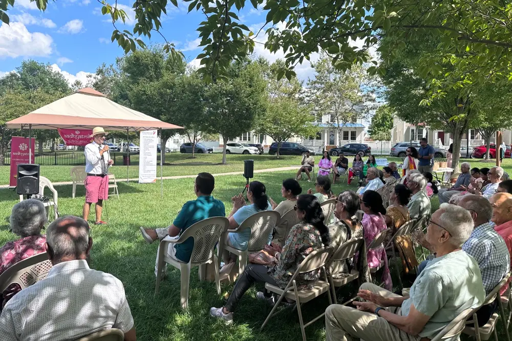 Seniors gathered on folding chairs under shade trees at a Sanskriti outdoor social